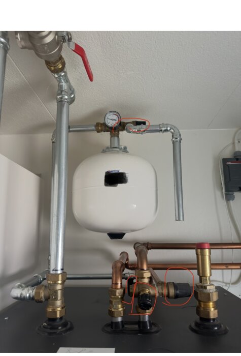 Manometer och rörledningar för en bergvärmepump, olika ventiler markerade för justering av tryck.