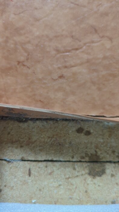 Golvmatta från badrum från 1974 borttagen vid tröskel, avslöjar ett enfärgat plastliknande material utan synliga lager.