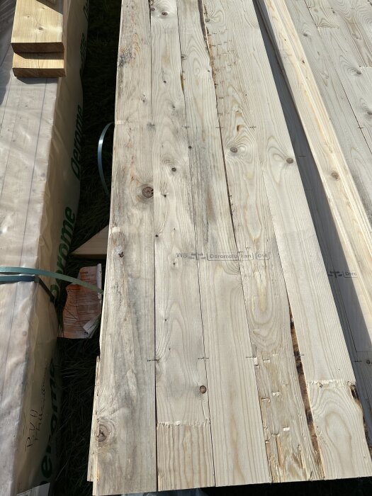 Torra träbrädor med vissa tecken på mögel i solen, omgivna av förpackningar.