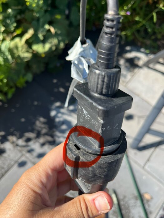 Svart kontakt av förlängningssladd med liten öppning, omgiven av silvertejp. Personen undrar om öppningen släpper in vatten.