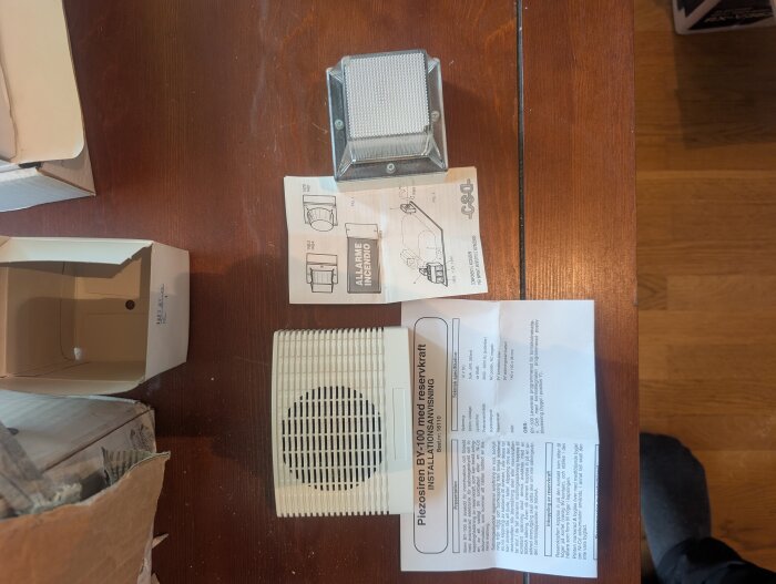 Gammalt larm från 90-talet med komponenter, instruktioner och förpackning på ett bord, redo att testas för installation.