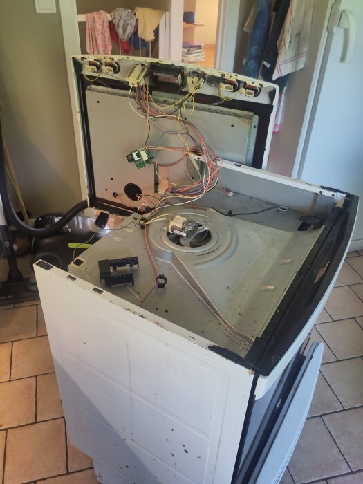 Öppen ugn med avmonterat bakstycke, exponerade kablar och komponenter för felsökning av kylfläkt och styrbox.