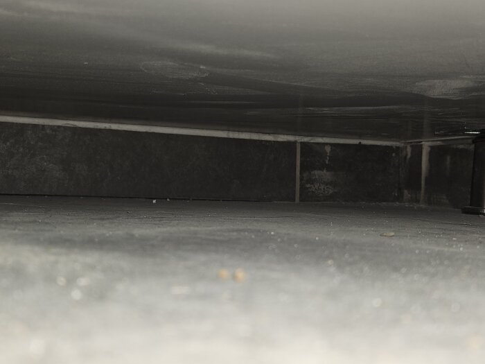 Närbild av ett hörn i ett badrum med kakel och fogar där det ser ut att saknas silikon runt botten av duschväggen, med osäkerhet kring tätning.