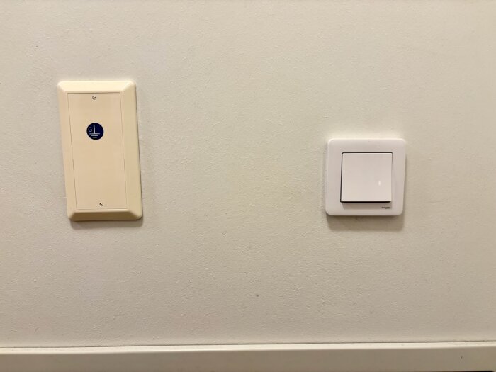 Gulnad strömbrytare till vänster jämfört med en vit Schneider Exxact strömbrytare till höger på en vit vägg.