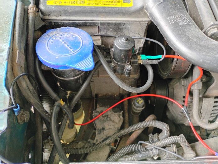 Motorutrymme med installerad extra spolarpump och kablar, samt lock för spolarvätska.