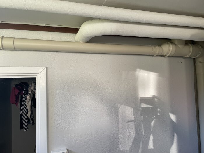 T-rör och rörsystem på vägg med minimal lutning, cirka 2 cm över två meter.