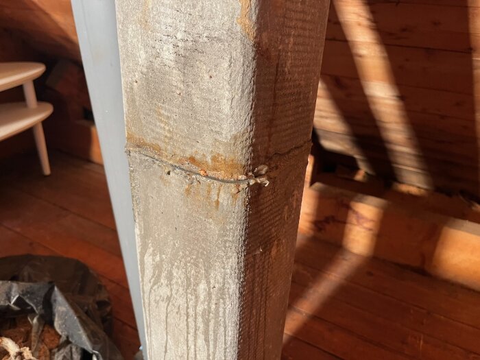 Närbild av en eternitkanal insmord med fett och vatten, monterad i ett trähus. Kanalen är sned men sitter fast ordentligt.