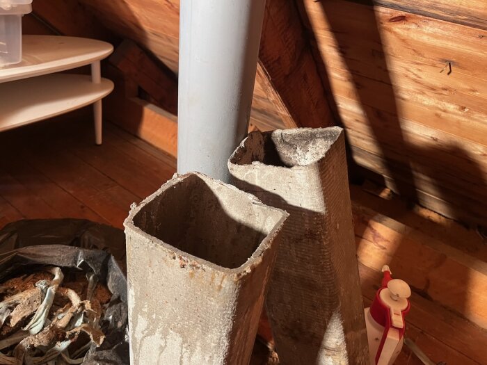 Gamla eternitrör sågade isär på vinden, med en ny Intellivent Fresh Sky-kanal installerad bredvid, och byggmaterial i fjärran.