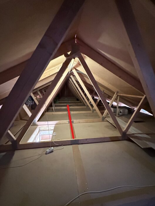 Bilden visar vinden med takstolar i fackverkskonstruktion. En röd linje markerar väggen som planeras rivas mellan kök och vardagsrum.