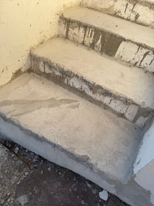 Ofärdig cementtrappa med ojämna steg och synliga formrester. Trappan verkar ha påbörjats men inte slutförts.