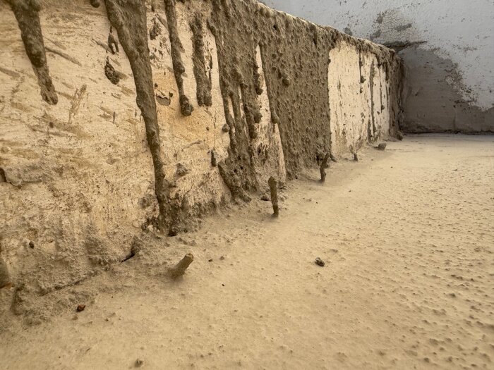 Gjuten cementtrappa med ojämna ytor och utskjutande armeringsjärn, visar pågående bygge som behöver slutföras.