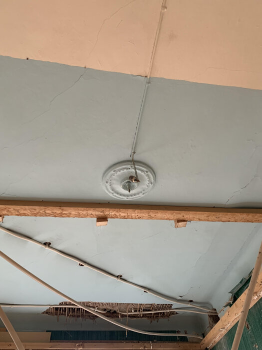 Gammal takrosett med synliga elkablar i ett rum där taket sänkts och originaldetaljer är bevarade under.