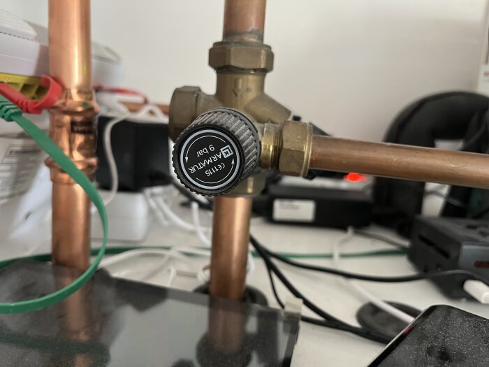 Rörsystem med kopparrör och ventil från märket Armatur, fotograferat från en annan vinkel med fokus på ventilen.