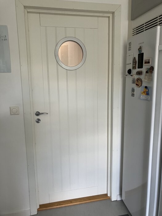 Omlackad dörr med runt fönster installerat.