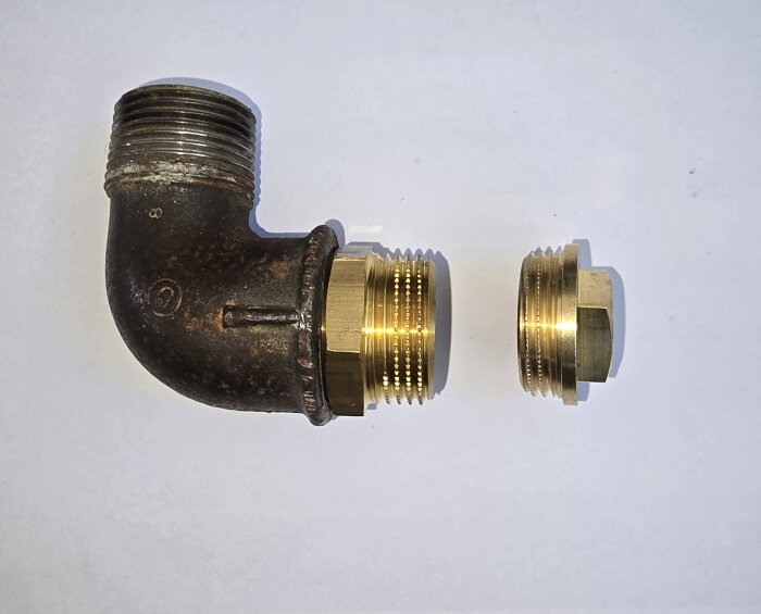 Gammal aducerad svart rördel och två mässingsdelar: renspropp med kort gänga och sexkant med normal längd.