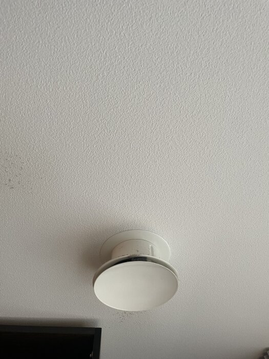 Tilluftsventil märkbart nedstickande från taket i relation till garderobsdörr.