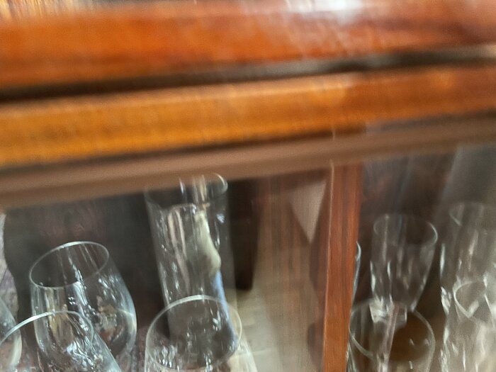 Glasskåp med glas som står osäkert på grund av nedsänkta spår, vilket kan leda till att glasen faller ut när de flyttas.