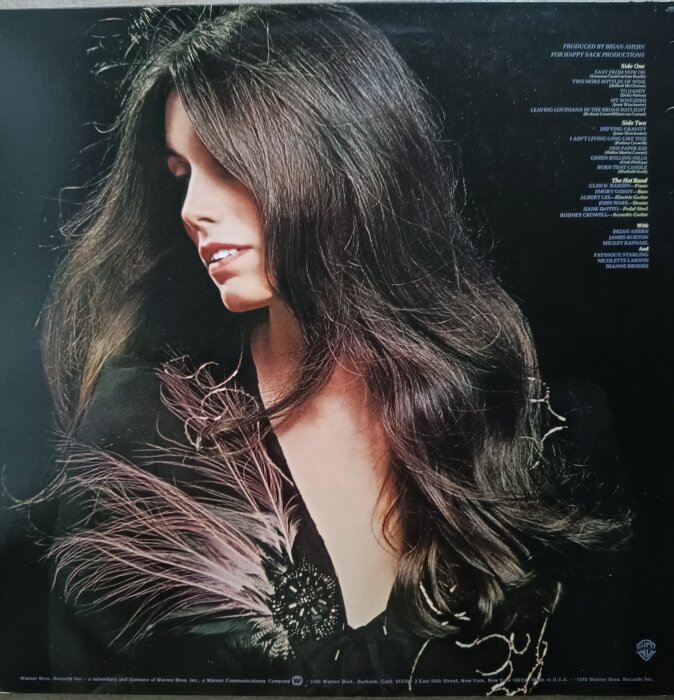 En kvinna med långt mörkt hår, iklädd fjäderdekorerad klädnad, fotograferad i profil.