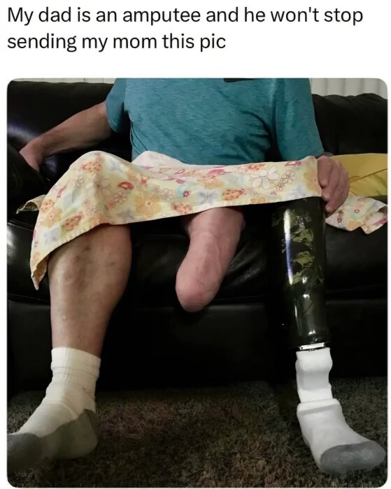 En man med benprotes sitter på soffan med en filt över benen.