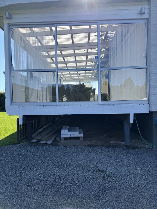 Altanens nedre del med trall och material staplat under, redo för bygge av trappa vid entrén.