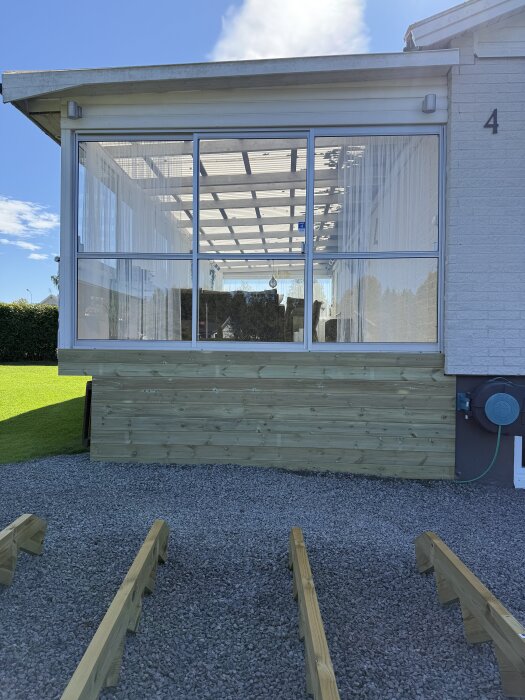 Altanen med glasväggar och nylagd liggande trall i trä, förberedelse för att bygga en ny entrétrappa.