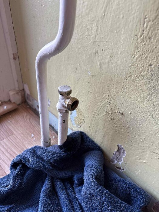 Gängat rör under element, omgiven av blå handduk, ska mätas för plugg, gängorna mäter 22mm.