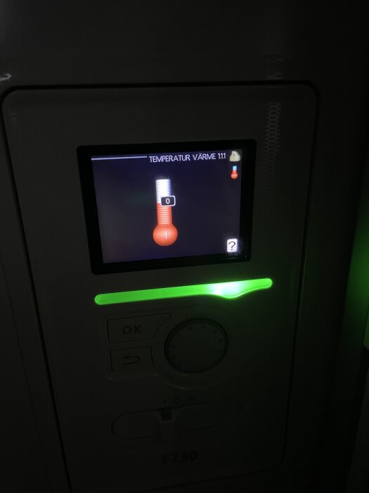 Display på en Nibe F730 värmepump som visar temperatur, med en ratt och knapp bredvid.