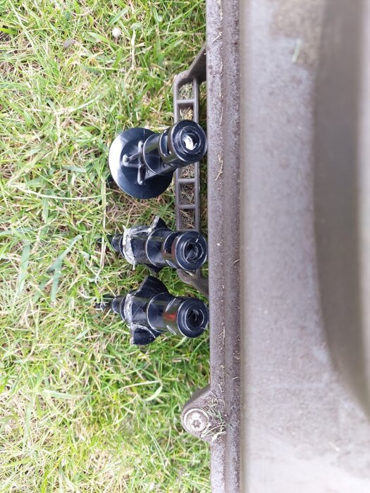 Roterande knivar på en gräsklippare, täckta med viss mängd gräsrester, på en gräsmatta.