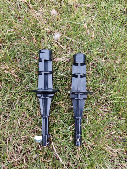 Svarta plastdelar från gräsklippare på gräsmatta, beskrivna som joystickar som kan orsaka rörelseproblem.