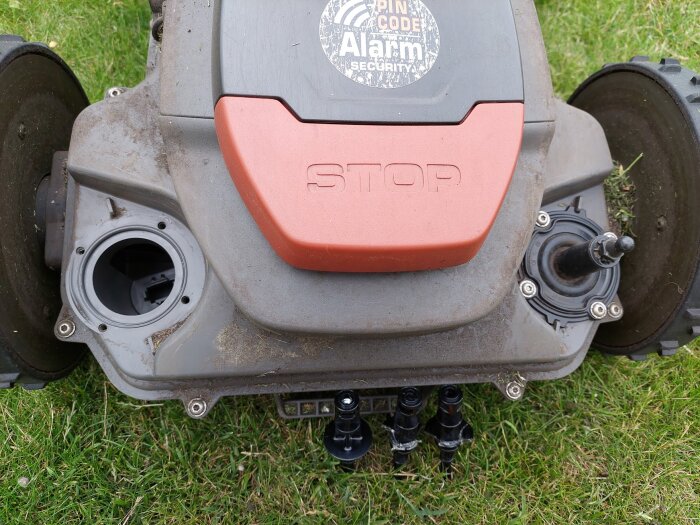 Gräsklippare utan kåpa med tydliga hjul och mekaniska komponenter, fotad på gräsmatta.