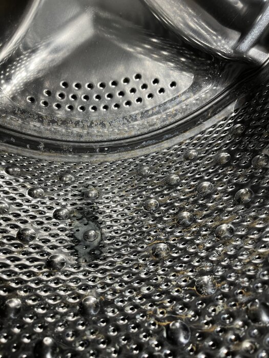 Insidan av en rostig tvättmaskintrumma med synliga vattenfläckar och rostangrepp.