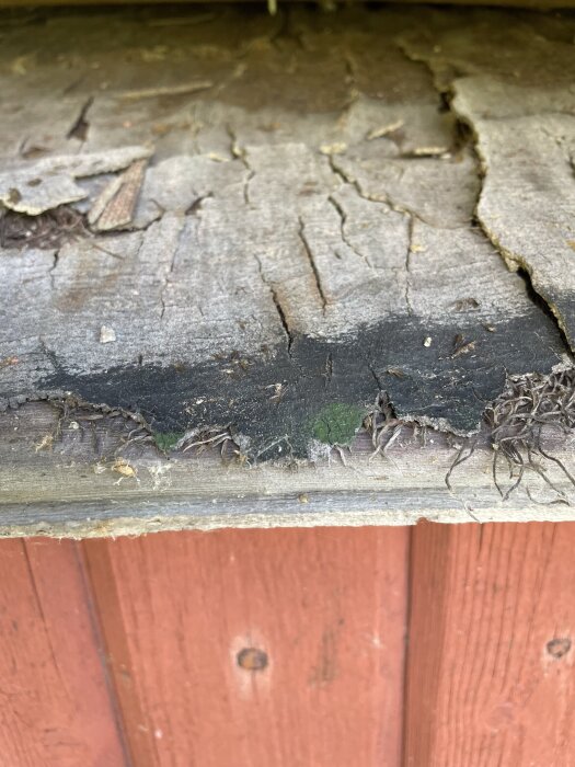 Sprucken, sliten yta under plåttak med utskjutande trådar, liknar juteväv.