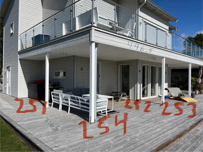 Altan med sittgrupp under balkong; mått är skrivna på trädäck.