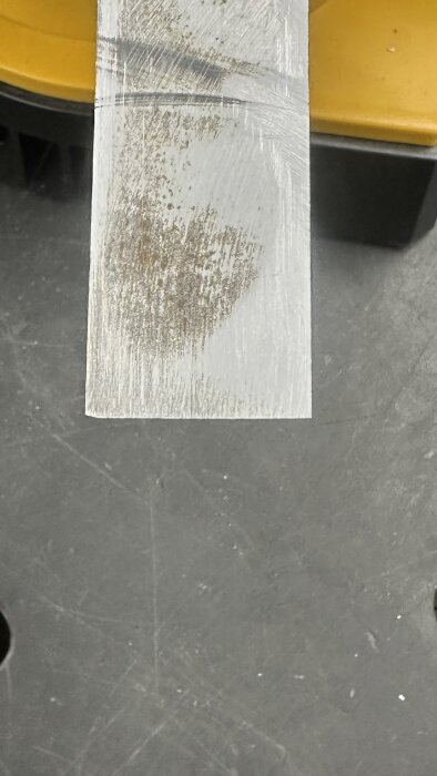 Nyslipat stämjärn med en spegling på bladet placerat över en grå yta, med ett gult inslag i bakgrunden.