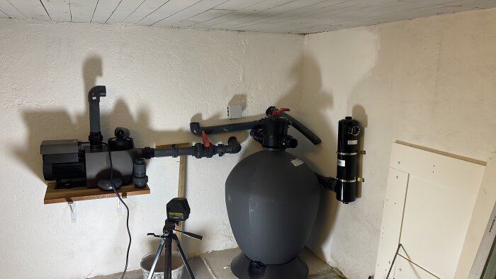 Poolteknikrum med pumpar och rör, installerade i ett källarutrymme med synliga ventiler och tankar.