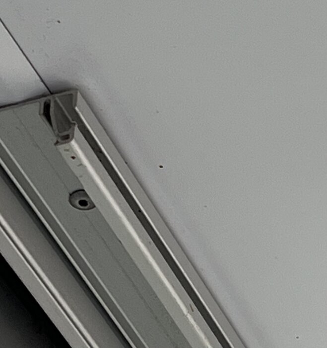 Gardinskena monterad i taket på en inglasad balkong, avsedd för att fästa gardiner som fungerar som solskydd.