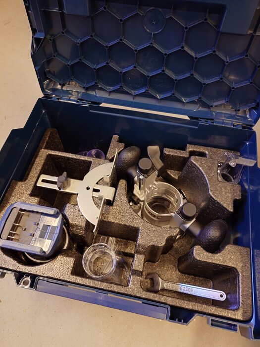 Öppen L-boxx med insats innehållande olika verktyg och tillbehör, inklusive sänkbas och splitterskydd för sticksågar.