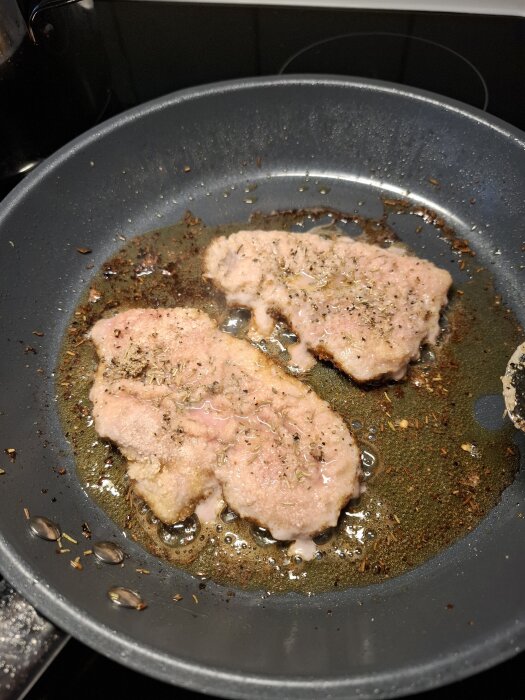 Stekta fläskschnitzlar i stekpanna, kryddade med citronpeppar, rosmarin och salt.