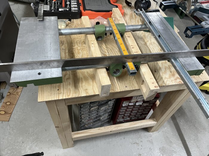 Arbetsbänk i trä med stålställning och fästanordning, verktyg och låda ses i bakgrunden.