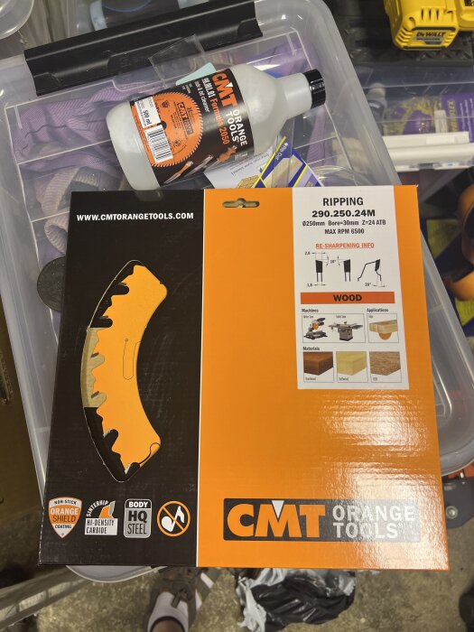 Förpackning av sågklinga från CMT Orange Tools samt en flaska rengöringsvätska på plastlåda i garage.
