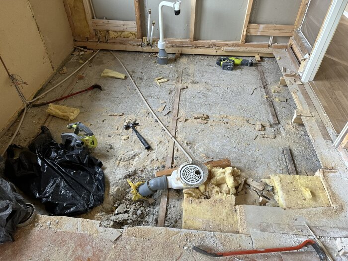 Renovering av badrum och sovrum med rivna väggar och golv, verktyg och byggmaterial synliga, omfattar byte av plast och omläggning av golvkonstruktion.
