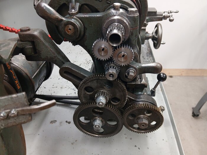 Gammal svarv med synliga kugghjul och axlar, en del av ett renoveringsprojekt där nya axlar med bussningar använts för att passa äldre Blomqvist-drev.