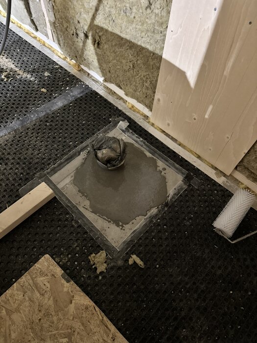 Trasigt PVC-rör omgivet av isolering och flytspackel på en byggarbetsplats där toalettens röranslutning ska fixas.