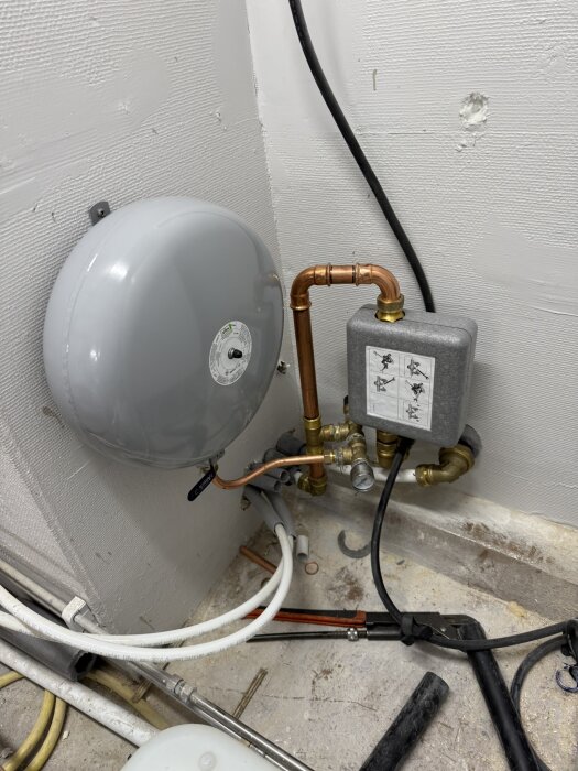 VVS-installation vid vägg, inklusive kopparrör och expanderkärl i ett byggprojekt.