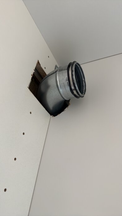 Rund frånluftskanal av metall installerad genom vägg i pågående renoveringsprojekt i tvättstuga.