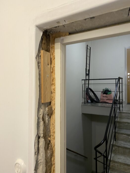 Lägenhetsdörr med synligt murbruk och träkonstruktion efter att plåtinklädnad tagits bort, visar behov av renovering till ursprungligt skick.