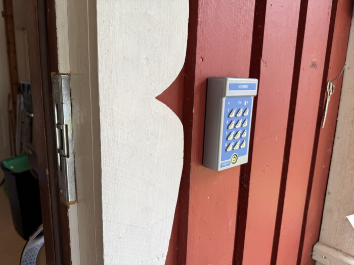 Kodlås installerat på en röd ytterdörr med ett elsutbleck monterat på dörrkarmen.