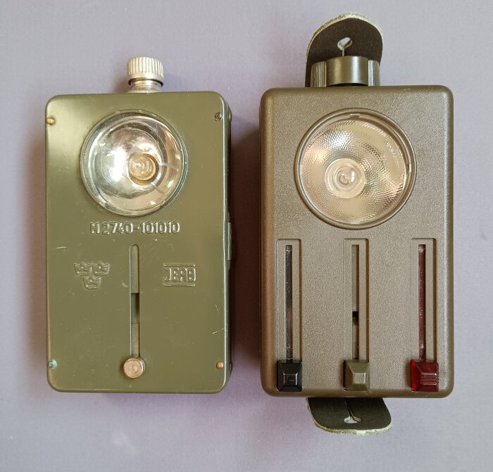 Två äldre ficklampor för 4,5 volts batteri bredvid varandra, en med röd och grönfilter för Lr14 batterier.