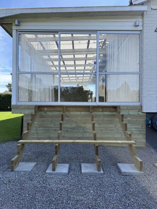 Trästomme för entrétrappa under byggnation framför ett hus, förberett för decklights och trallbrädor, på en grusbelagd yta.