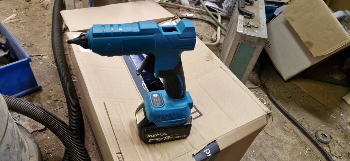 Makita smältlimpistol placerad på en kartong i en verkstadsmiljö.